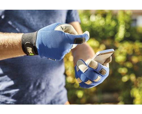 Une personne portant des gants de travail utilise un smartphone.