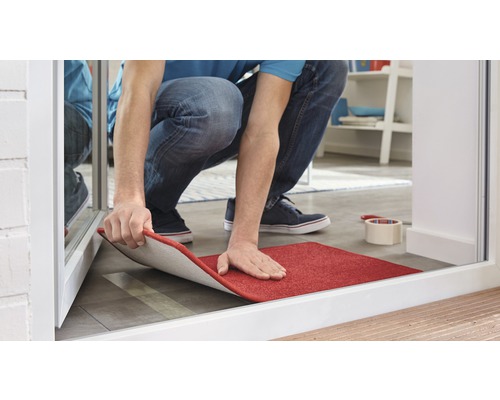 Un homme pose un tapis rouge dans l''entrée.