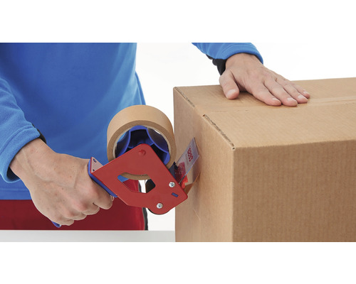 Eine Person verschließt einen Karton mit einem Handabroller und braunem Klebeband.