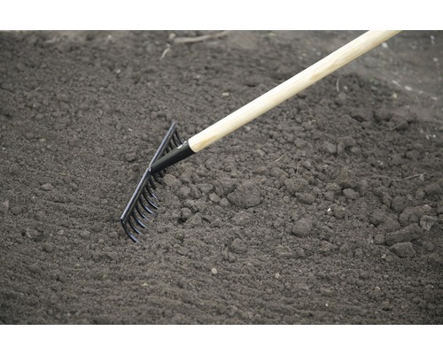 Râteau de jardin avec manche en bois utilisé sur la terre