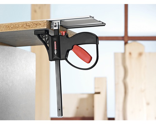 Logo Bosch. Pièce fixée au rail de guidage avec une pince à une main Bosch.