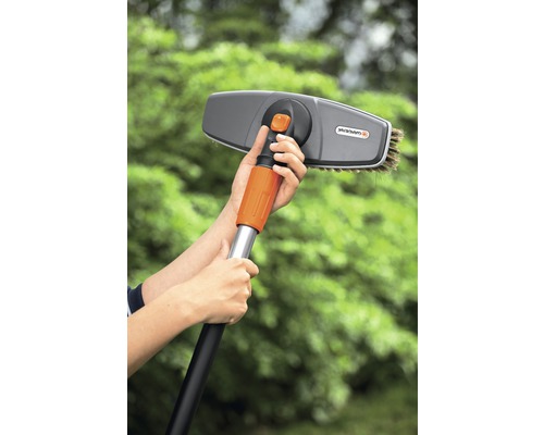 Une personne tient une brosse de lavage avec manche télescopique de Gardena.