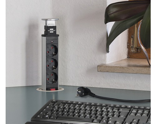 Bloc multiprise escamotable avec trois prises sur un bureau.