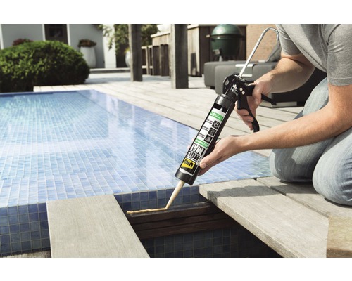 Handwerker verwendet Klebstoff aus einer Kartusche zum Verkleben eines Holzdecks neben einem Pool.
