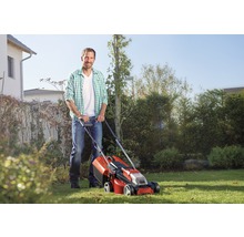 Ein Mann benutzt einen Rasenmäher im Garten.
