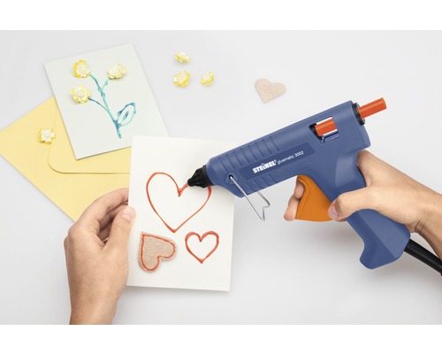 Person benutzt Heissklebepistole zum Basteln von Karten