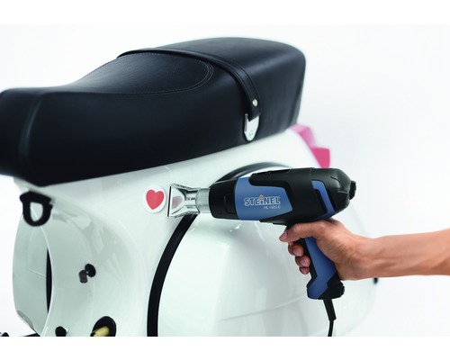 Pistolet thermique pour appliquer un autocollant sur un scooter.