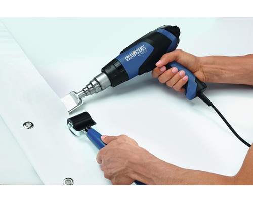 Personne soude une bâche avec un pistolet à air chaud et un rouleau de pression