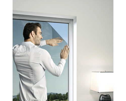 Ein Mann bringt Sonnenschutzfolie auf einer Fensterscheibe an.