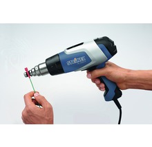 Une personne utilise un pistolet thermique Steinel HL 2020 E pour chauffer un câble