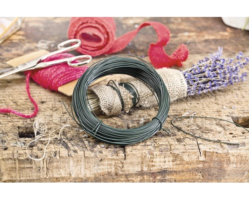 Spule mit Basteldraht, Blumendraht, Schere, Blumenseide und Lavendelstrauß auf Holztisch