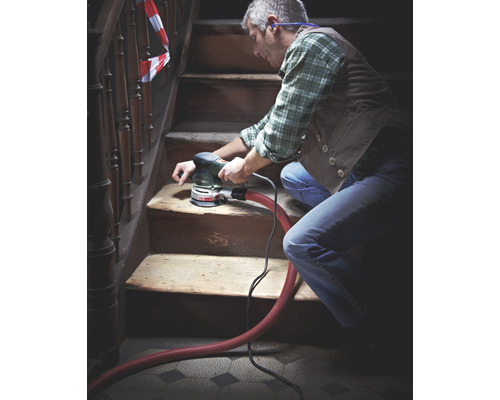 Homme ponçant un escalier en bois avec une ponceuse