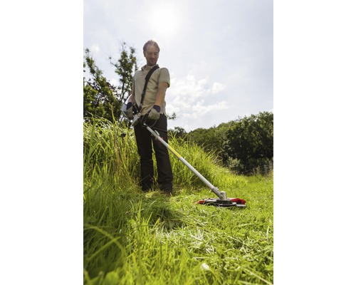 Un homme travaille avec un coupe-bordure dans le jardin.