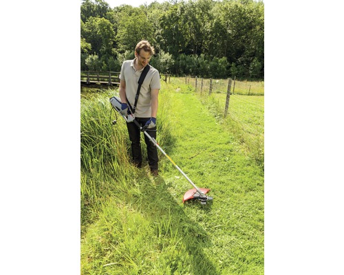 Un homme travaille avec un coupe-bordure dans le jardin