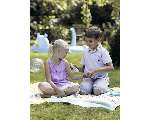 Un garçon vaporise un produit anti-moustiques sur le bras d''une fille dans le jardin.