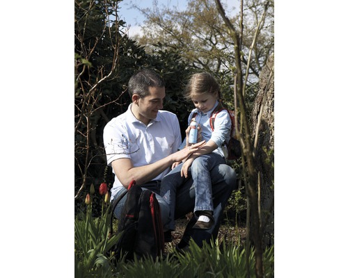 Un père applique un spray anti-insectes sur le bras de sa fille, alors qu''ils sont assis dehors.