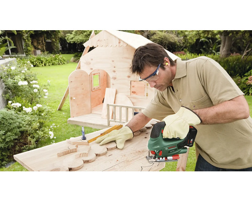 Homme coupant du bois avec une scie sauteuse pour une maison en bois