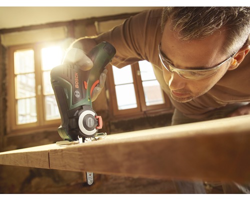 Un homme scie une planche de bois avec une scie sauteuse sans fil Bosch