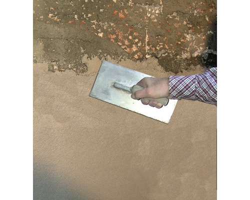 Handwerker glättet Putz mit einer Glättkelle an einer Wand