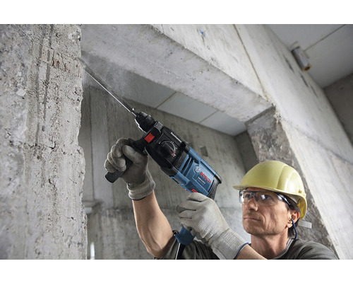Un homme perce un mur en béton avec un perforateur Bosch