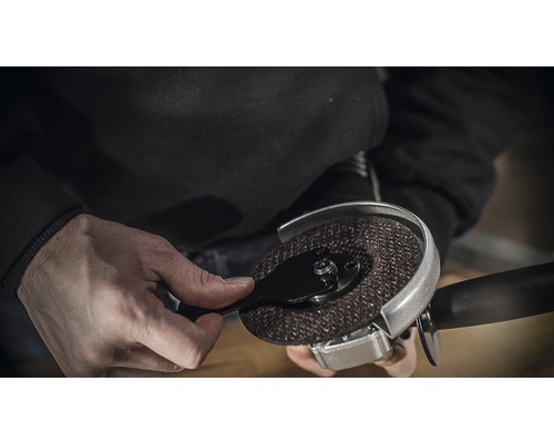 Une personne fixe un disque à tronçonner sur une meuleuse d''angle.