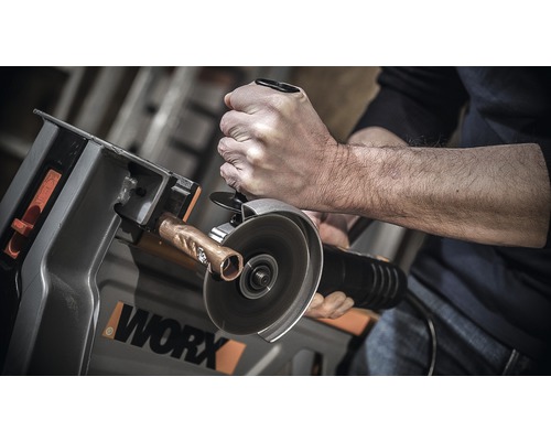 Un homme coupe un tube de cuivre avec une meuleuse à tronçonner sur un porte-pièce de la marque Worx.