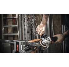 Ein Mann benutzt einen Winkelschleifer an einem Metallstück, das in einem Schraubstock befestigt ist.