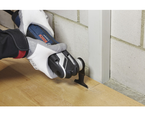 Une personne utilise un outil multifonction Bosch pour couper du bois.