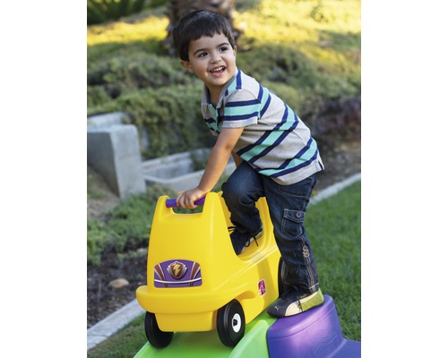 Enfant jouant avec une voiture à glissière jaune dans le jardin