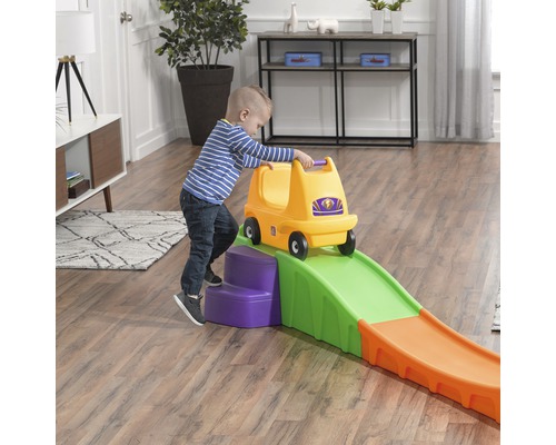 Enfant avec une voiture de glisse jaune sur des montagnes russes jouet à l''intérieur