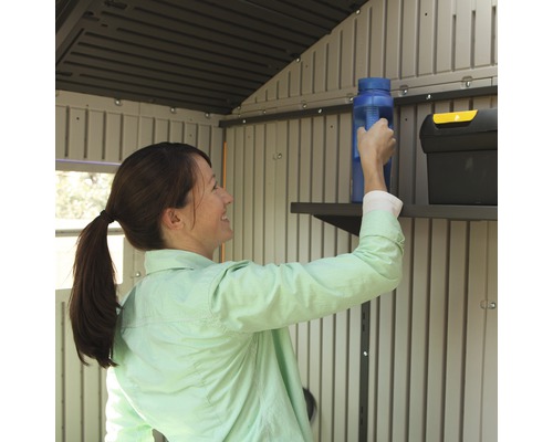Une femme range des ustensiles sur une étagère dans une cabane de jardin