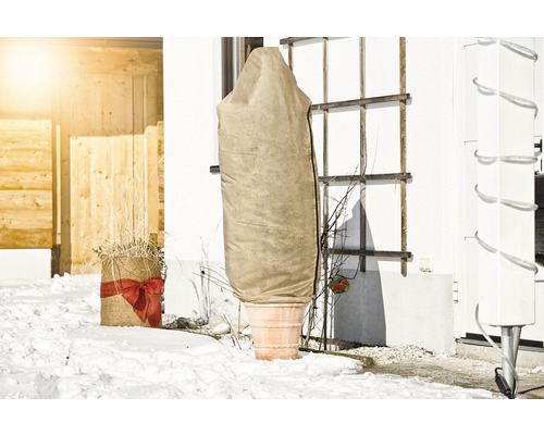 Pot de fleurs avec housse de protection hivernale dans un jardin enneigé