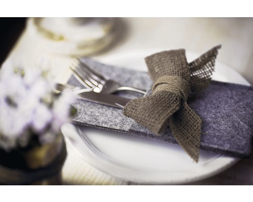 Table dressée avec des couverts dans une housse en feutre et un nœud