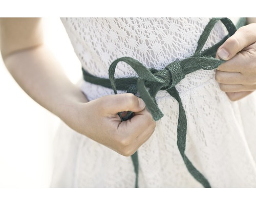 Femme nouant un nœud sur une robe blanche