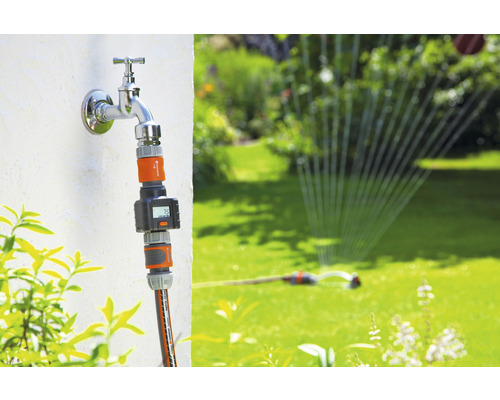 Gartenszene mit Wasserhahn, Bewässerungsuhr und Rasensprenger