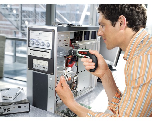 Un homme répare un ordinateur avec un tournevis sans fil Bosch.