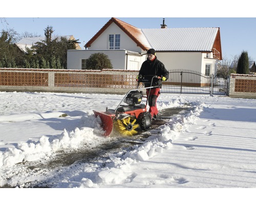 Un homme déblaie la neige devant une maison avec une souffleuse à neige