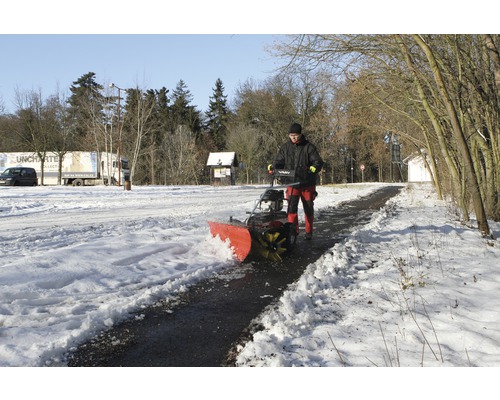 Un homme utilise une souffleuse à neige pour déneiger un chemin.