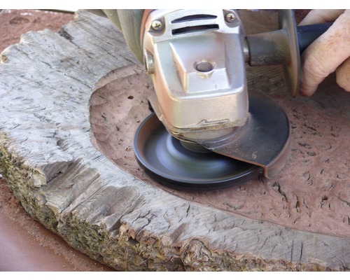 Handwerker bearbeitet ein Holzstück mit einem Winkelschleifer.