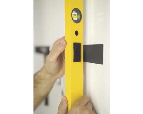 Eine gelbe Wasserwaage wird an einer Wand ausgerichtet.