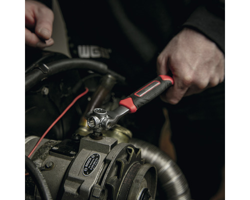 Eine Person benutzt einen Steckschlüssel an einem Motor.