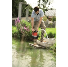 Un homme utilise une pompe à eau sale au bord d''une étendue d''eau.