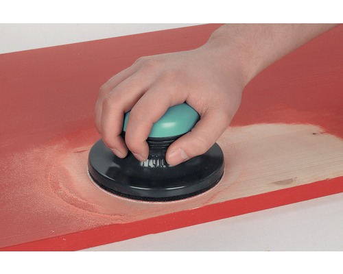 Personne ponçant une planche de bois avec une ponceuse manuelle