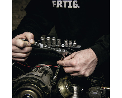 Une personne utilise une clé à cliquet et une douille pour effectuer des réparations sur un moteur de voiture.