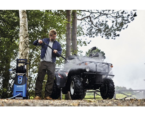 Homme nettoie un quad avec un nettoyeur haute pression à l''extérieur.