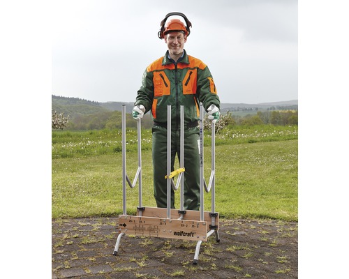 Un homme portant des vêtements de protection se tient derrière un range-bois Wolfcraft installé à l''extérieur.