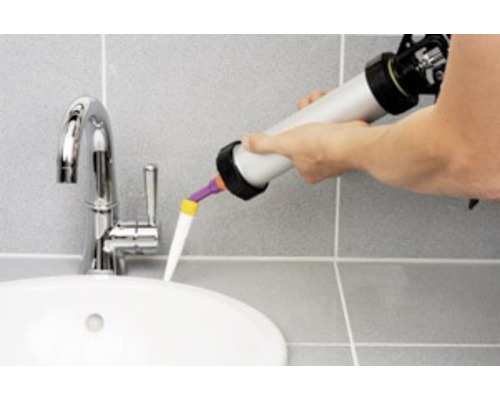 Auftragen von Dichtstoff mit einer Kartuschenpistole an einem Waschbecken