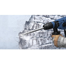 Ein Arbeiter benutzt einen Abbruchhammer, um eine Wand zu bearbeiten.