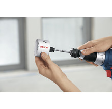 Une personne fixe une scie cloche de la marque Bosch sur une perceuse.