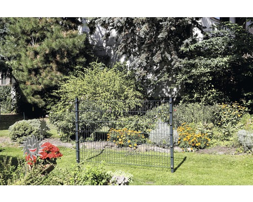 Gartenszene mit Zaunelement aus Metall vor blühenden Büschen